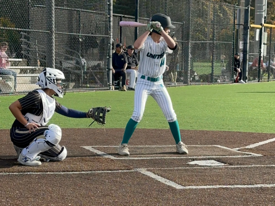 Softball batter at home plate with catcher during a game.